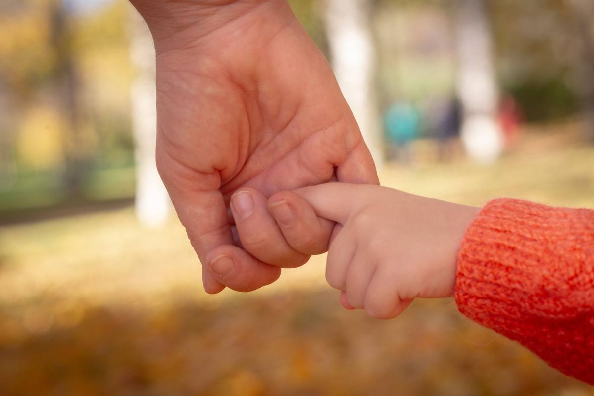 Mano de un adulto que sostiene la mano de un niño